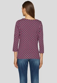 Mehrfarbiges, geometrisch gemustertes Oberteil mit Dreiviertelärmeln. Hergestellt aus leichtem Stoff, mit Rundhalsausschnitt und taillierter Form.