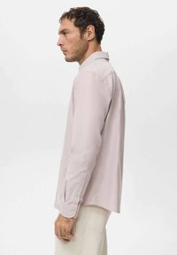Camisa de manga larga color rosa claro con cuello puntiagudo, puños con botones y un ajuste relax. Confeccionada en tela suave con una superficie ligeramente texturizada.