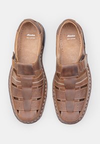 Barna bőr slip-on cipők, kivágott mintával, varrott díszítéssel és párnázott talppal. Belül "Bata VALÓDI BŐR" felirat található.