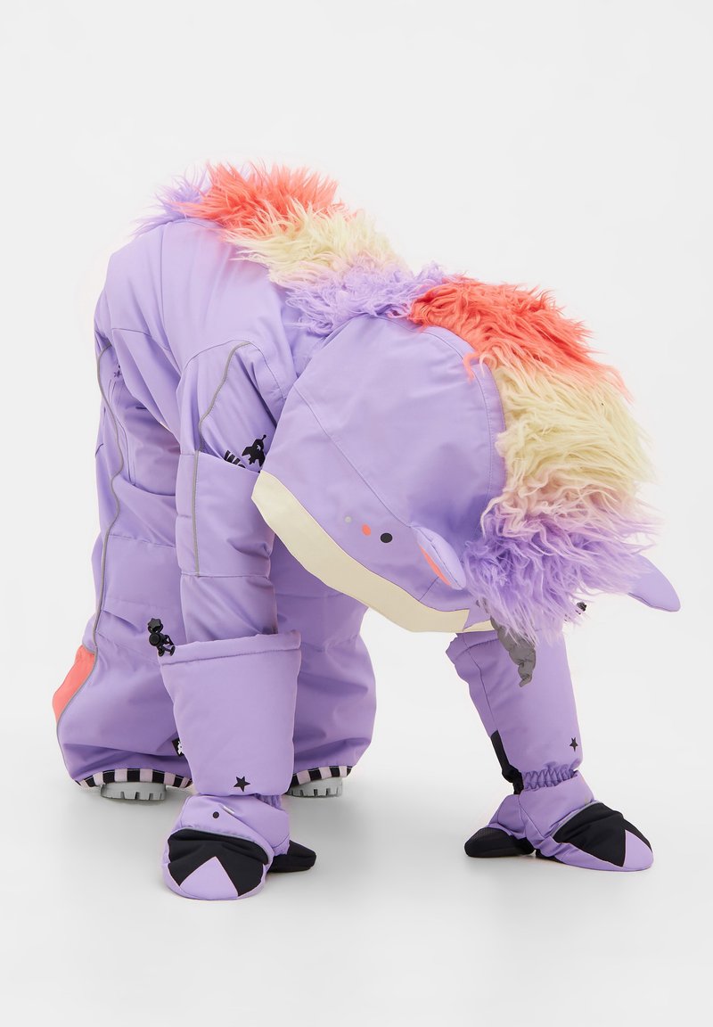 Lila sn overall med en fluffig flerfärgad huva, svarta accenter och en unik djurdesign. Har elastiska ärmslut och dragkedjefickor.