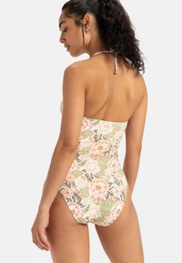 Eén stuk badpak met bloemen in pastelroze en groen, strapless ontwerp, textuurstof en hoge beenopeningen.
