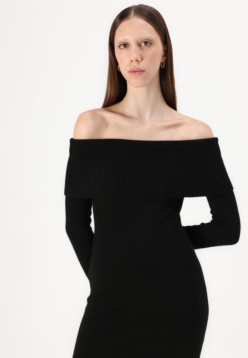 Schwarzes Strickkleid mit einem schulterfreien, gerippten Ausschnitt und langen Ärmeln. Glatte Oberfläche, figurbetonte Silhouette.