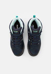 Paire de bottes de randonnée imperméables bleu marine avec semelles noires, rembourrage intérieur bleu clair et lacets noirs, vues de dessus sur fond blanc.