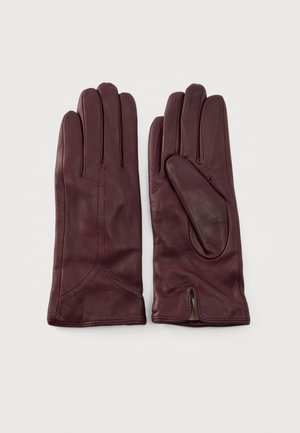 Un par de guantes de cuero color burdeos, colocados en posición vertical sobre un fondo claro, con las costuras y un fuelle lateral a la vista.