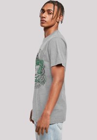 Grijze katoenen T-shirt met een ronde hals, korte mouwen, met een groen grafisch ontwerp en ingewikkelde zwarte accenten op de voorkant.