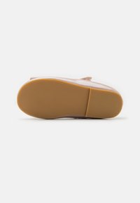 Suela de goma de un zapato, con un color marrón claro y un patrón texturizado y estriado para tracción y durabilidad. Bisel superior suave.