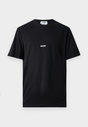 Camiseta de algodón negra con cuello redondo y mangas cortas. En la parte frontal se muestra un logo blanco de "MSGM" centrado. Textura suave, ajuste estándar.