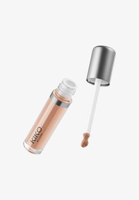 KIKO Milanon peitevoideputki, jossa on hopeinen korkki ja applikaattoritanko, joka sisältää persikkasävyistä peitevoidetta valkoisella taustalla.