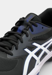 Černá sportovní bota s šedými a fialovými akcenty, s texturovaným síťovým svrškem, černými tkaničkami a výrazným bílým logem.