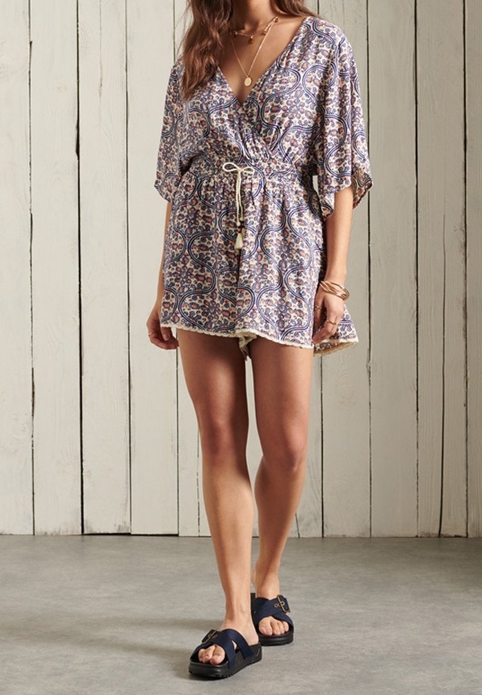 Floral wrap dress in lightweight fabric, featuring a V-neck and short sleeves, with a drawstring waist and patterned design. Paired with dark sandals.
