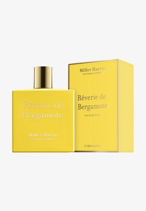 Bouteille de parfum rectangulaire jaune avec un capuchon doré et un texte en relief. Accompagnée d'une boîte jaune assortie avec des accents argentés.