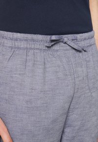 Světle šedé teplákové kalhoty z měkké látky s elastickým pasem a nastavitelným stahováním, s texturovaným povrchem a bočními kapsami.