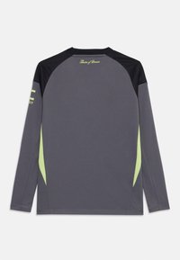 Chemise à manches longues grise avec des accents noirs. Présente des panneaux latéraux vert citron et un design de texte au dos. Tissu doux et lisse avec une coupe décontractée.