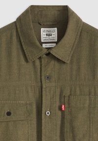 Olive green herringbone patterned shirt with a pointed collar, button closure, chest pocket, and red Levi's label. Standard relaxed fit.