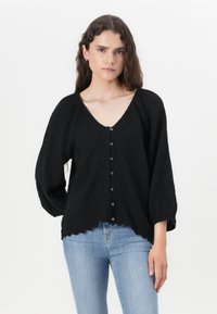Black textured blouse with a V-neck, puffed long sleeves, and a row of buttons down the front, featuring embroidered floral details at the neckline.