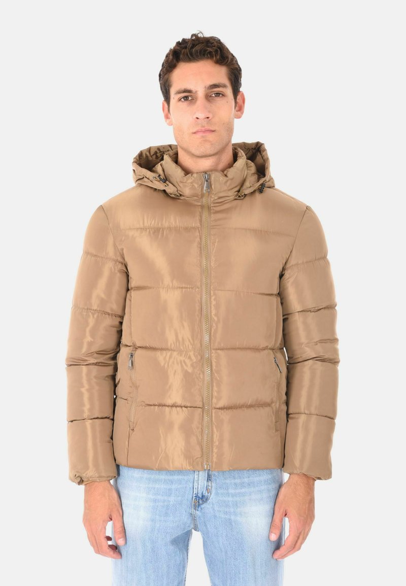 Giacca a soffietto marrone con collo alto e zip, caratterizzata da un cappuccio e pannelli cuciti; texture liscia e lucida. Indossata sopra jeans blu.