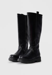 Knee-high black leather boots with a smooth texture, side zipper, and thick rubber sole. Minimalist design with rounded toe.