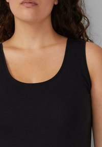 Schwarzes ärmelloses Tanktop mit rundem Ausschnitt und glatter Textur, eng am Körper anliegend und mit minimalen Designelementen.