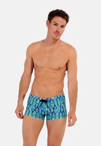 Schwimmshorts mit blauem Grund und bunten Surfbrett-Mustern. Das Material ist leicht und enganliegend, mit einem elastischen Bund und Kordelzug.