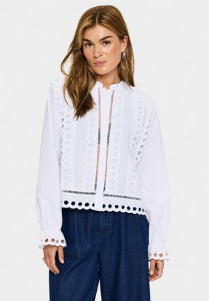 Weiße Bluse mit kreisförmigen Ausschnitten, einem Stehkragen und langen Ärmeln mit Wellenabschlüssen. Texturiertes Gewebe mit lockerer Passform.