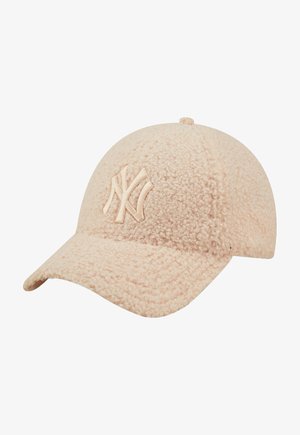 Lyse beige struktureret baseballkasket med buet skygge og hævet New York Yankees logo på frontpanelet.