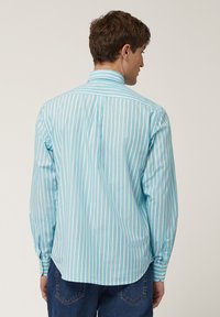 Heren overhemd met lange mouwen in lichtblauw met verticale strepen. Voorzien van een button-down kraag, een rugplooitje en manchetten met één knoop.