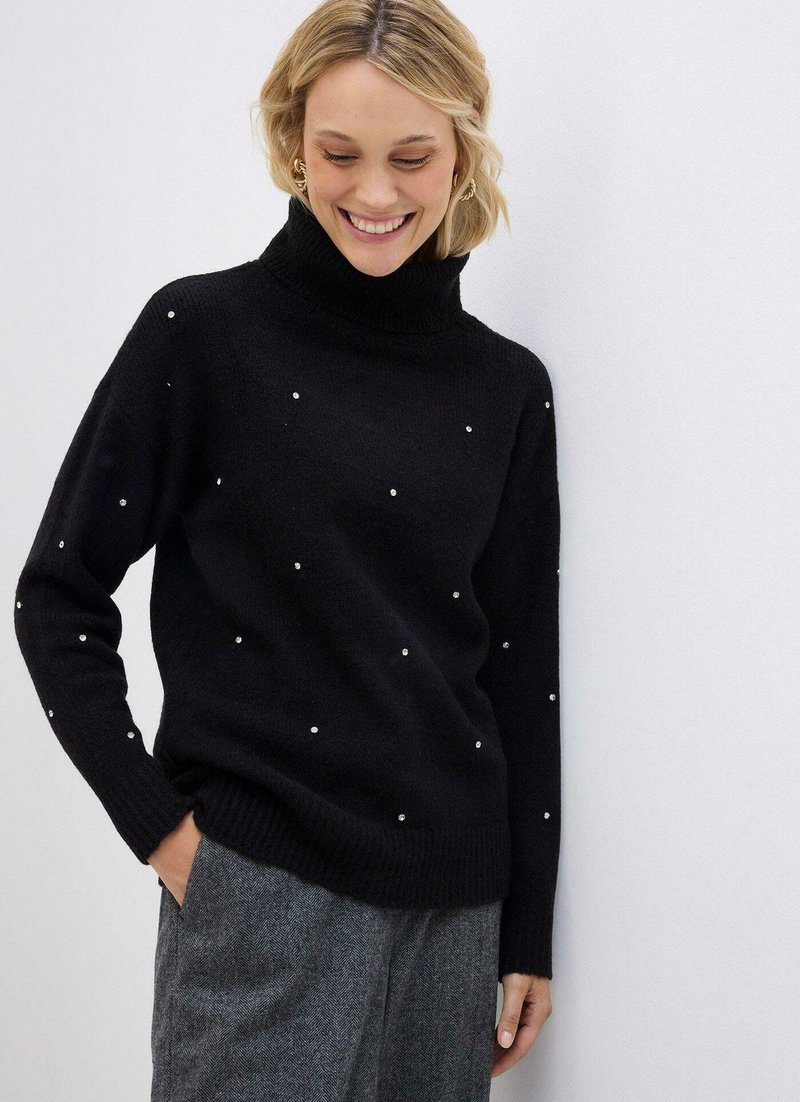 Maglione a collo alto di colore nero con dettagli simili a perle, realizzato in morbido materiale di maglia. Presenta maniche lunghe e una vestibilità rilassata.