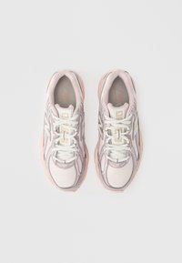 Rózsaszín és fehér New Balance futócipők párja, felülről nézve, egyszerű fehér háttéren.