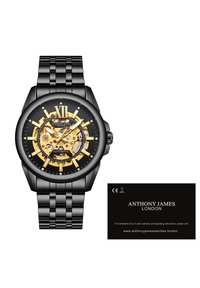 Zwarte roestvrijstalen horloge met een skeletdial, gouden accenten en Romeins cijfer XII. Voorzien van een schakelarmband en merkkaart.