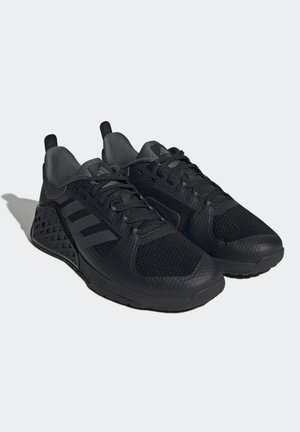 Paire de baskets noires avec des panneaux en mesh et texturés, design à lacets et trois bandes diagonales sur le côté, inclinées vers la gauche sur un fond clair.