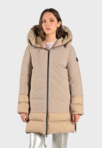 Beige pufferjack met een brede capuchon, een rits over de volledige lengte en een contrasterende lichtere zoom. Beschikt over een gladde textuur en zijzakken.