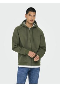 Olivgrön zip-hoodie med tvåfärgad huva, framfickor, ribbade mudd och nederkant, tillverkad av mjuk, texturerad tyg.