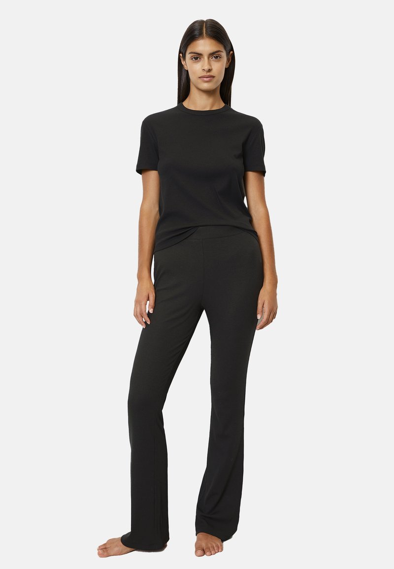 Top negro de manga corta y pantalones ajustados, fabricados con un material suave y elástico. Diseño simple con escote redondeado y sin patrones ni acentos visibles.