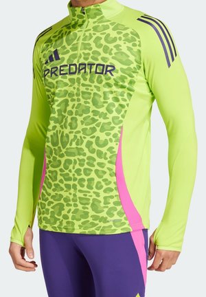 Jasnozielony sportowy top z długim rękawem, z przodu z nadrukiem w panterkę, różowe boczne panele, fioletowe paski Adidas na rękawach oraz logo "PREDATOR" na piersi.