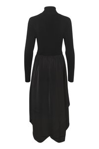 Svart kjole med en tettsittende strikket topp med høy krage, som går over til en flytende satengskjørt med asymmetrisk nederkant.