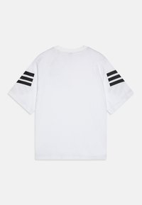 Camiseta de algodón blanca con mangas raglán, que presenta tres rayas horizontales negras en cada manga y un cuello redondo.