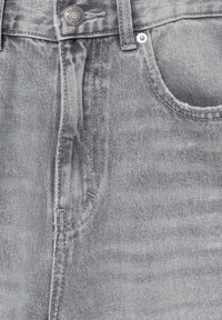 Jean en denim gris avec une poche avant, une fermeture à bouton métallique et un léger effet délavé. Le tissu présente une texture lisse avec des surpiqûres contrastées.