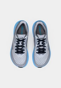 Scarpe sportive grigie con dettagli blu; tomaia in mesh, trama a motivi, lacci a contrasto e logo sulla linguetta. Suola arrotondata e ammortizzata.