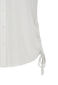 White blouse with a button front, drawstring side detail, and a smooth texture. Features gathered fabric along the sides for adjustable fit.