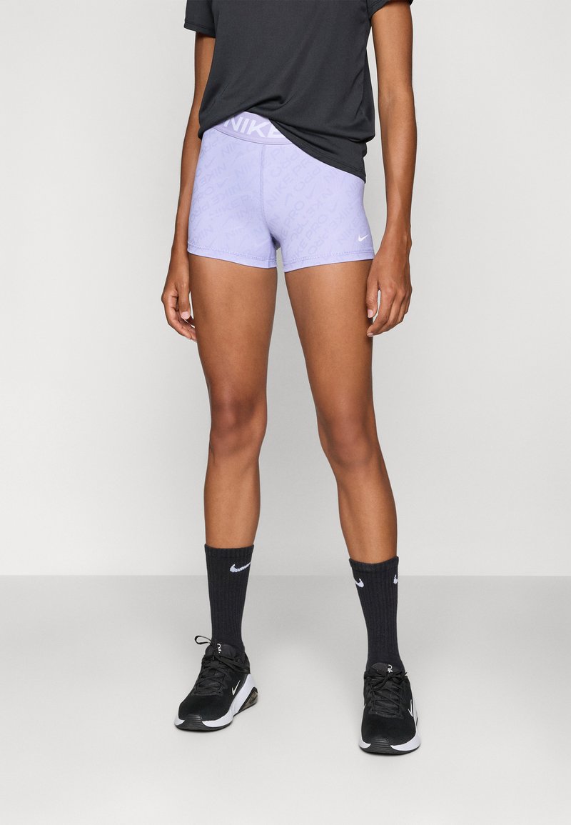 Nike purple athletic shorts with textured pattern, elastic waistband, and white logo; paired with black socks and shoes. Simple design.