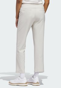 Φωτεινό μπεζ παντελόνι με κομψή εφαρμογή, με ομαλή υφή, δύο πίσω τσέπες και cropped μήκος, σε συνδυασμό με λευκά παπούτσια.