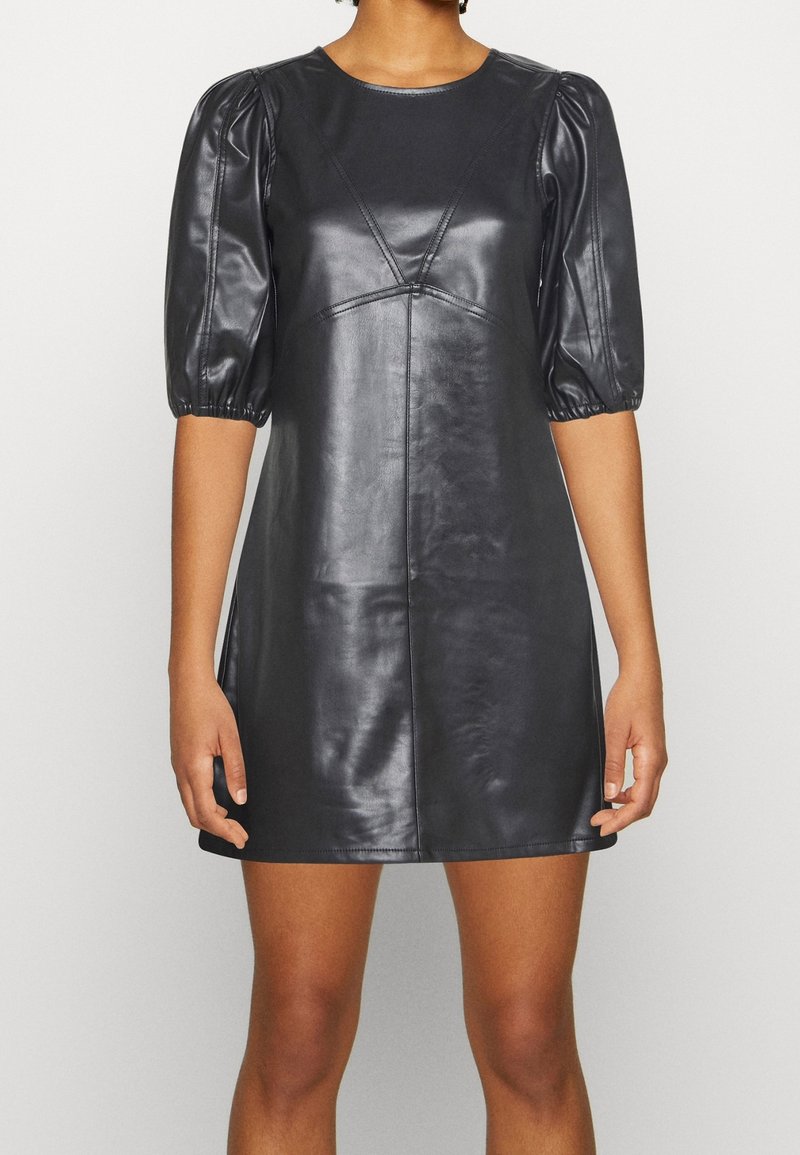 Czarna skórzana sukienka z dopasowanym gorsetem, okrągłym dekoltem i krótkimi bufkami. Powierzchnia ma gładką teksturę z przeszyciami.