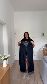 Temno modri, denim kavbojke, držane pokončno, z razkrivanjem designa ravanih nog. Vidni so podrobnosti šivov in pas z zankami za pas.