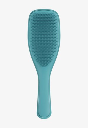 Brosse à cheveux en plastique bleu avec des poils flexibles uniformément espacés et une poignée ergonomique sur fond blanc.