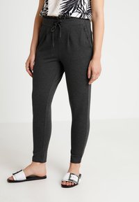 Mörkgrå joggingbyxor med dragsko i midjan, sidofickor och texturerat detaljer. Matchas med vita slides med svart sula och spänne.