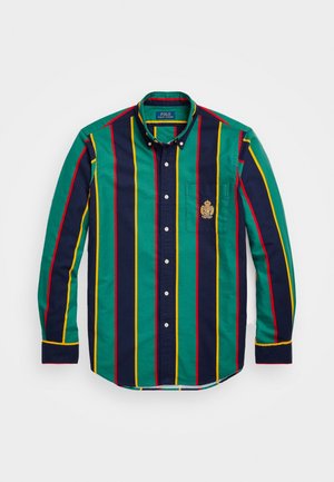 Long-sleeve button-up shirt with green, navy, red, and yellow vertical stripes and an embroidered crest on the left chest pocket.
