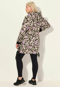 Beige met paarse accenten, lang mouw hooded jack met luipaardprint; gecombineerd met zwarte leggings en schoenen; bevat trekkoorddetails.