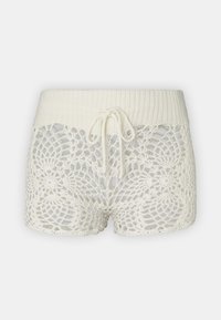 White crochet shorts with a ribbed waistband and drawstring. Features intricate lace patterns and a semi-sheer texture.