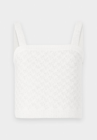 White knitted crop top with a square neckline, featuring textured patterns and wide ribbed straps. Soft fabric with subtle sheen.