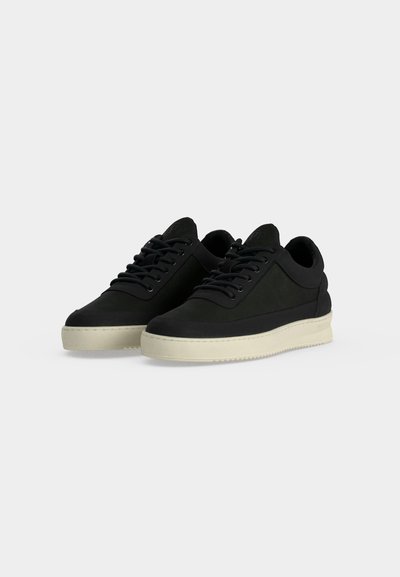 Ζευγάρι μαύρα παπούτσια τύπου low-top με μαύρα κορδόνια και εκρού λαστιχένιες σόλες σε απλό ανοιχτό φόντο.